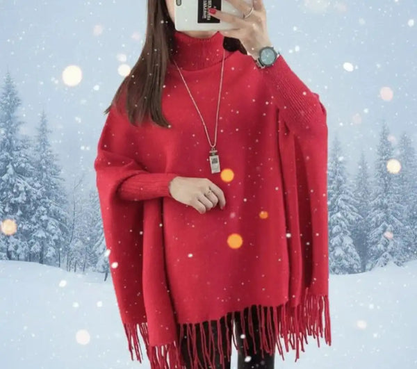 Person wearing a red poncho with tassels in a snowy landscape