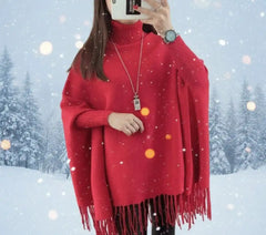 Person wearing a red poncho with tassels in a snowy landscape
