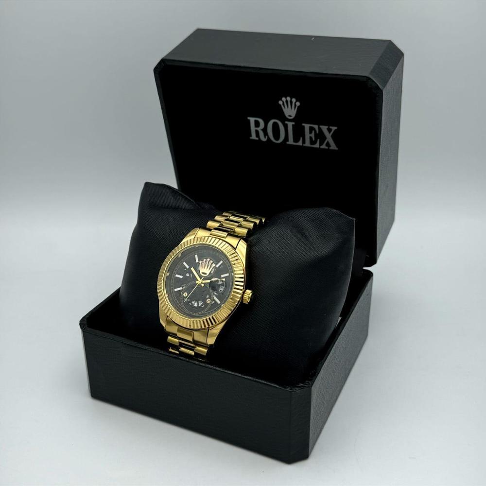 Gold watch in a black Rolex box on a light gray background
