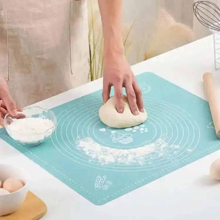 Person kneading dough on a blue silicone baking mat with kitchen items in the background. Online Sale In Pakistan